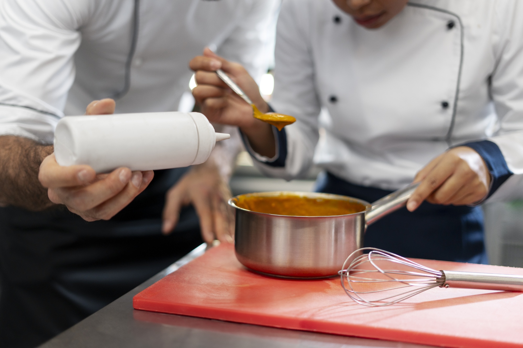 Teacher demonstrating sauce technique in kitchen